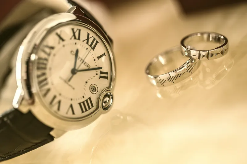 Aus dem Sand geborgene Armbanduhr neben mehreren Ringen